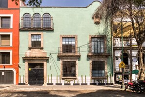A row of colorful buildings with distinct architectural styles, including a green building with a black gate and a red building with a white door.