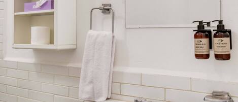 A bathroom with a white sink, a toilet, a towel rack, a mirror, and two bottles of hand soap.