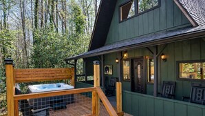 En træterrasse med jacuzzi, en stentrappe og en veranda med stole og en dør.