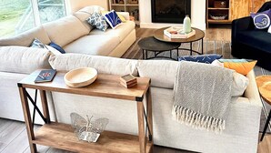 Ein modernes Wohnzimmer mit einer großen Couch, einem Couchtisch, einem Fernseher und einem Bücherregal.