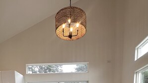 Ein Essbereich mit einem Holztisch, grünen Stühlen und einer gewobenen Pendelleuchte.