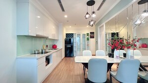 A modern kitchen with white cabinets, a dining table with chairs, and a refrigerator.