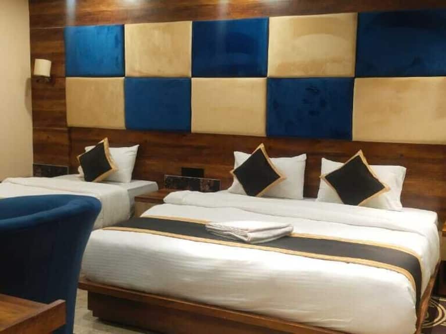 Una habitació d'hotel amb dos llits, un butàc blau i un panell de fusta amb disseny blau i beix.