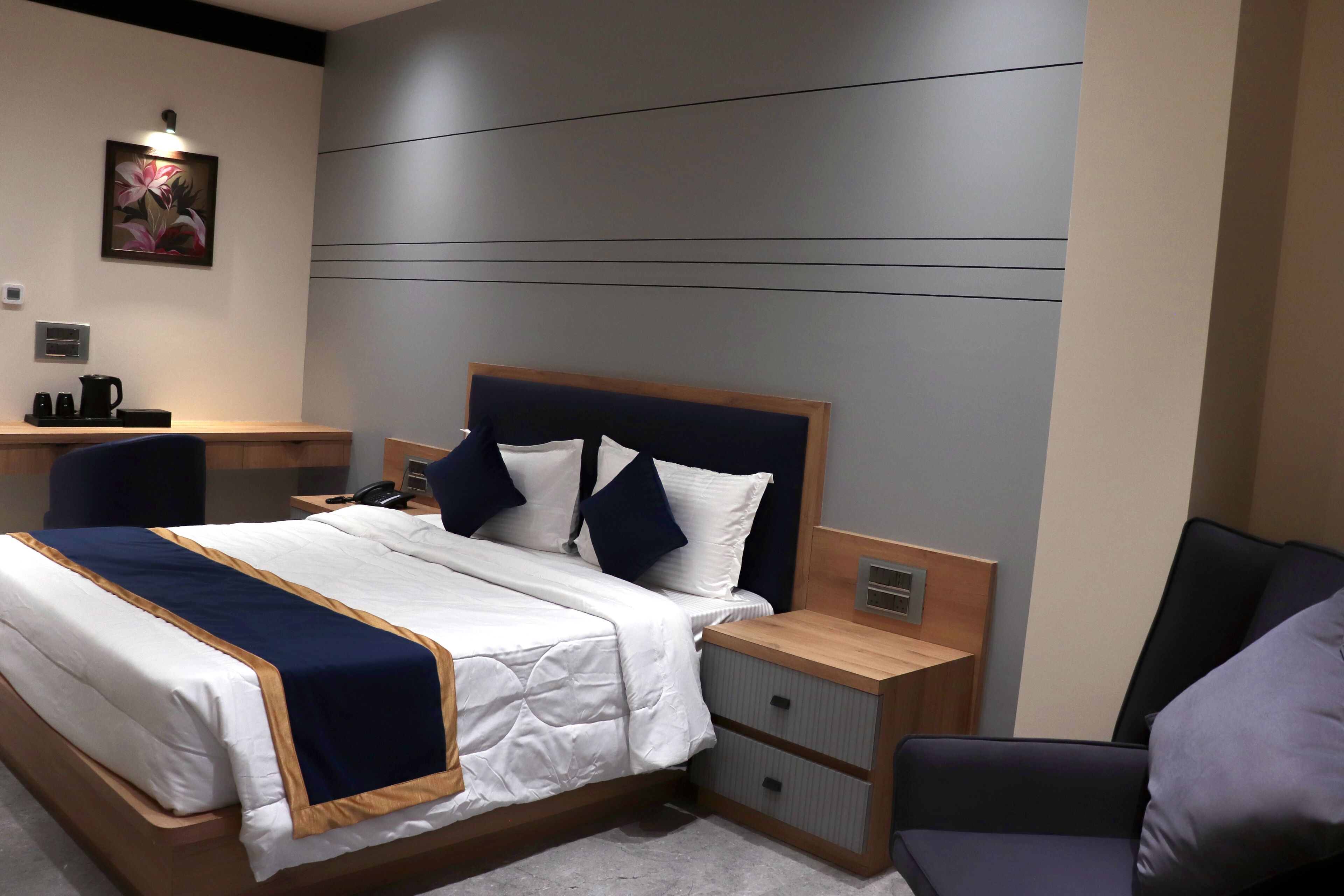 Una habitación de hotel moderna con una cama bien hecha, una mesita de noche con lámpara y una silla.
