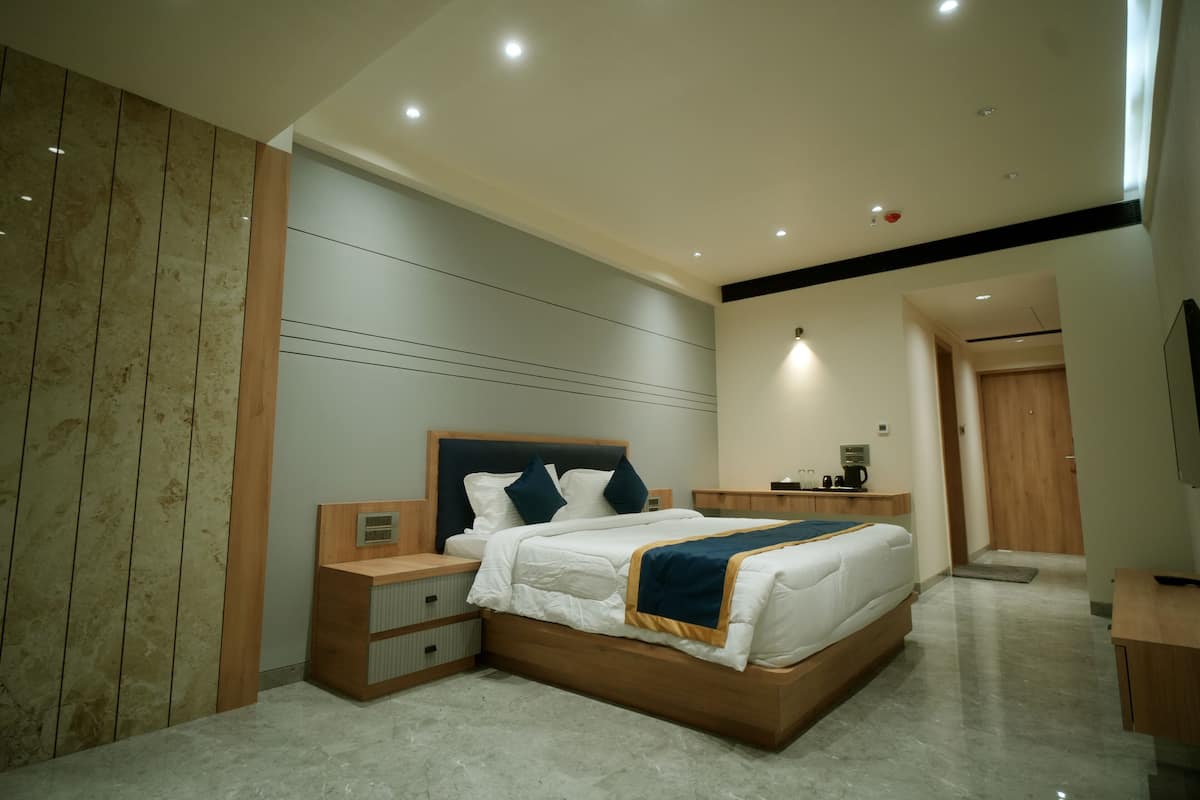 A modern bedroom with a large bed, wooden nightstands, a bedside table, and a built-in headboard.