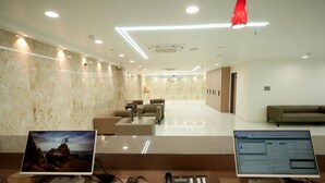 A modern reception area with two desktop computers, a telephone, and a small desk area with a keyboard and mouse. - Dream Inn By Spring Tree (Wadhwan)