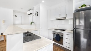 A modern kitchen with white cabinetry, a stainless steel refrigerator, a built-in oven, and a countertop with a sink. - Central 2BR APT for 6PPL, w/ free parking@SouthBNE (South Brisbane)