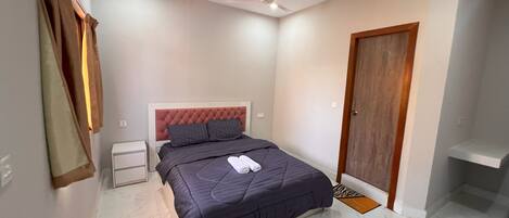 A bedroom with a bed, a nightstand, a wardrobe, and a ceiling fan.