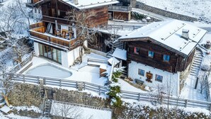 A snow-covered multi-story wooden building with balconies and a swimming pool.