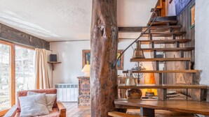 A cozy living area with a wooden staircase, a cushioned bench, and a tiled floor.