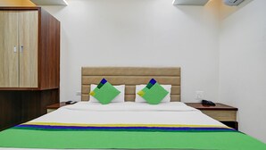 Une chambre d’hôtel avec un lit, une armoire en bois et une table de chevet avec un téléphone.