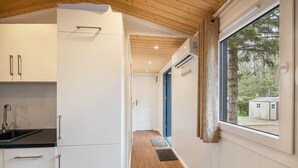 Une cuisine moderne avec des armoires blanches, un plan de travail noir et un plafond en bois.