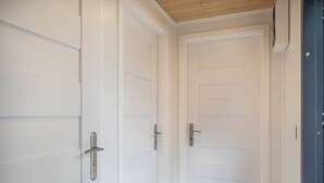 Un couloir avec des portes blanches, un plafond en bois et une porte bleue sur la droite.