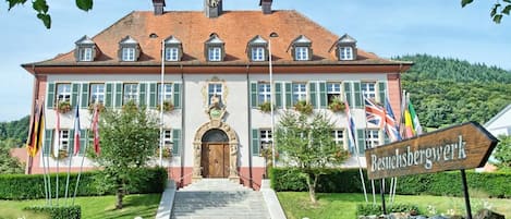 A large building with a central entrance, multiple windows, and a flag display.