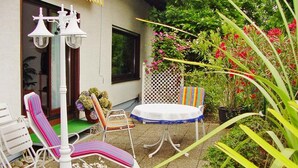 Un patio con mesa y sillas, un farol y una variedad de plantas y flores.