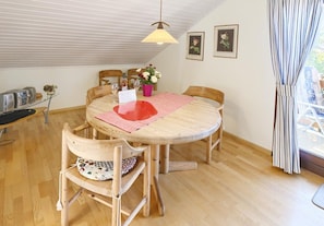 A dining area with a round wooden table, chairs, and a hanging lamp. - Haus Sonnenschein – Apartment 3 with Air Conditioning (Bad Krozingen)
