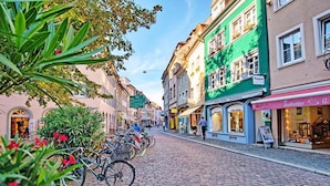 A cobblestone street lined with colorful buildings, a row of bicycles, and a few pedestrians.
