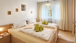 A hotel room with two beds, a nightstand, a wardrobe, and a window with curtains.