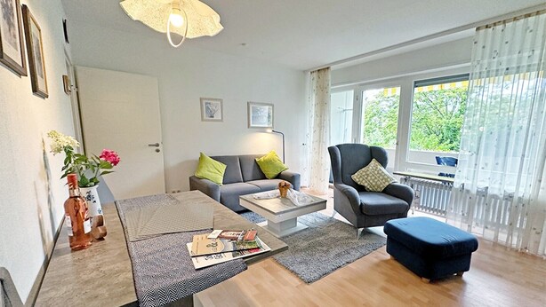A modern living room with a sofa, armchair, coffee table, and ottoman.