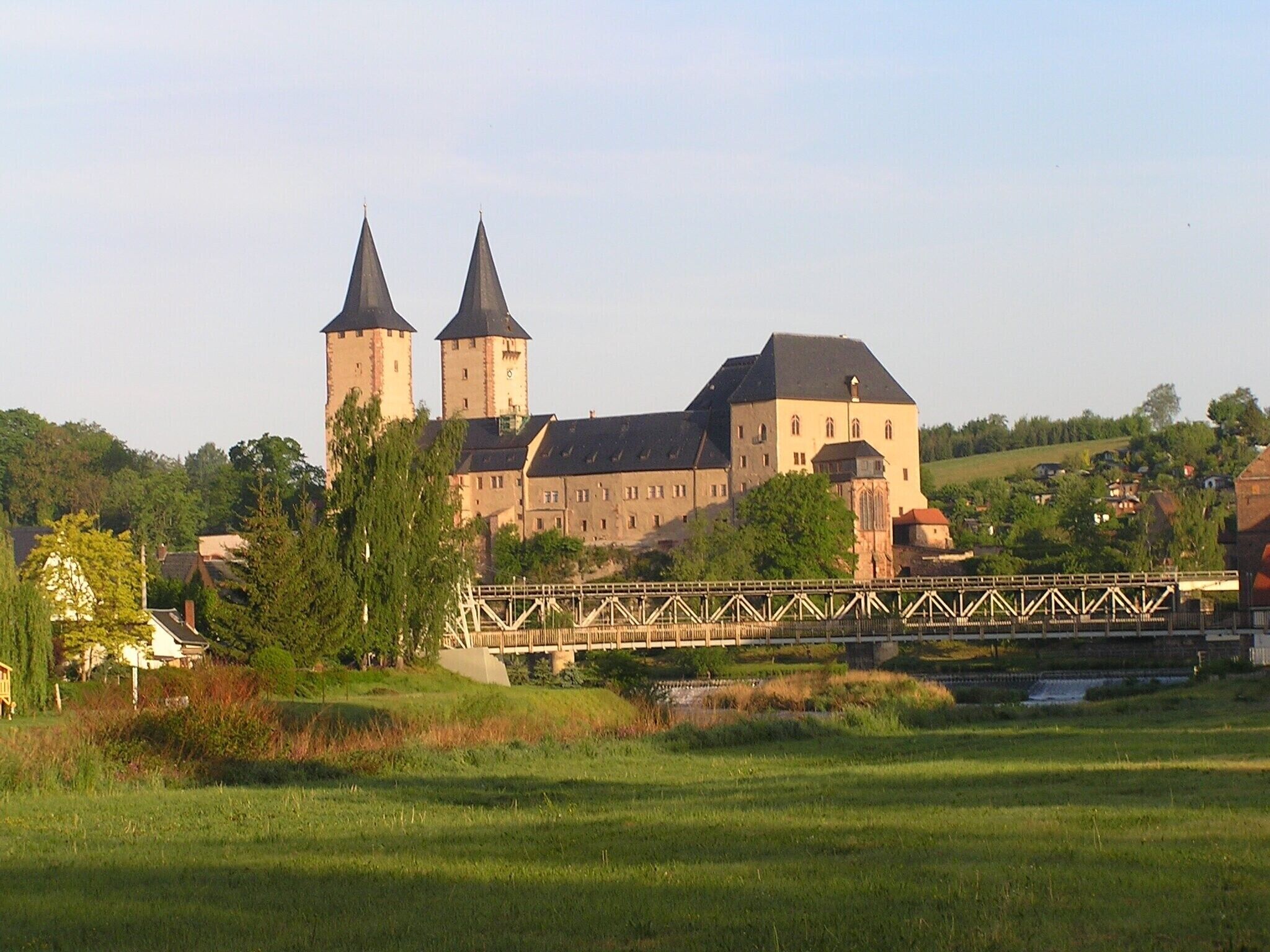 Eine große Burg mit zwei Türmen, einer Brücke und einem Fluss.