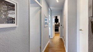 A hallway with a framed picture, a door, and a kitchen in the background. - Apartment 'Hexe 4 ' with Balcony and Wi-Fi (Braunlage)
