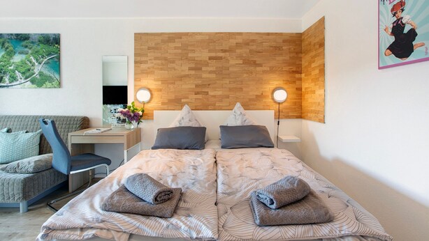 Een moderne hotelkamer met een groot bed, een bureau, een stoel en een tv aan de muur.