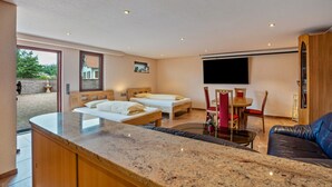 A modern room with two beds, a dining area, and a TV mounted on the wall. - Studio Apartment 'Haus Am Bächel 2' with Shared Terrace and Wi-Fi (Sasbach)
