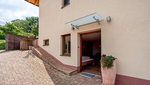 A building with a patio area, a glass door entrance, a small outdoor seating area, and a potted plant. - Studio Apartment 'Haus Am Bächel 2' with Shared Terrace and Wi-Fi (Sasbach)