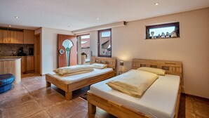 A bedroom with two wooden beds, a small kitchenette, and a window with a view of a building. - Studio Apartment 'Haus Am B ächel 2' with Shared Terrace and Wi-Fi (Sasbach)
