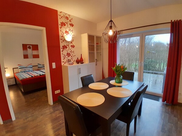 Un espace repas moderne avec une table en bois, des chaises et un vase de fleurs.