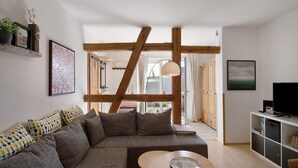 A living room with a sofa, a coffee table, a TV, and a bookshelf.