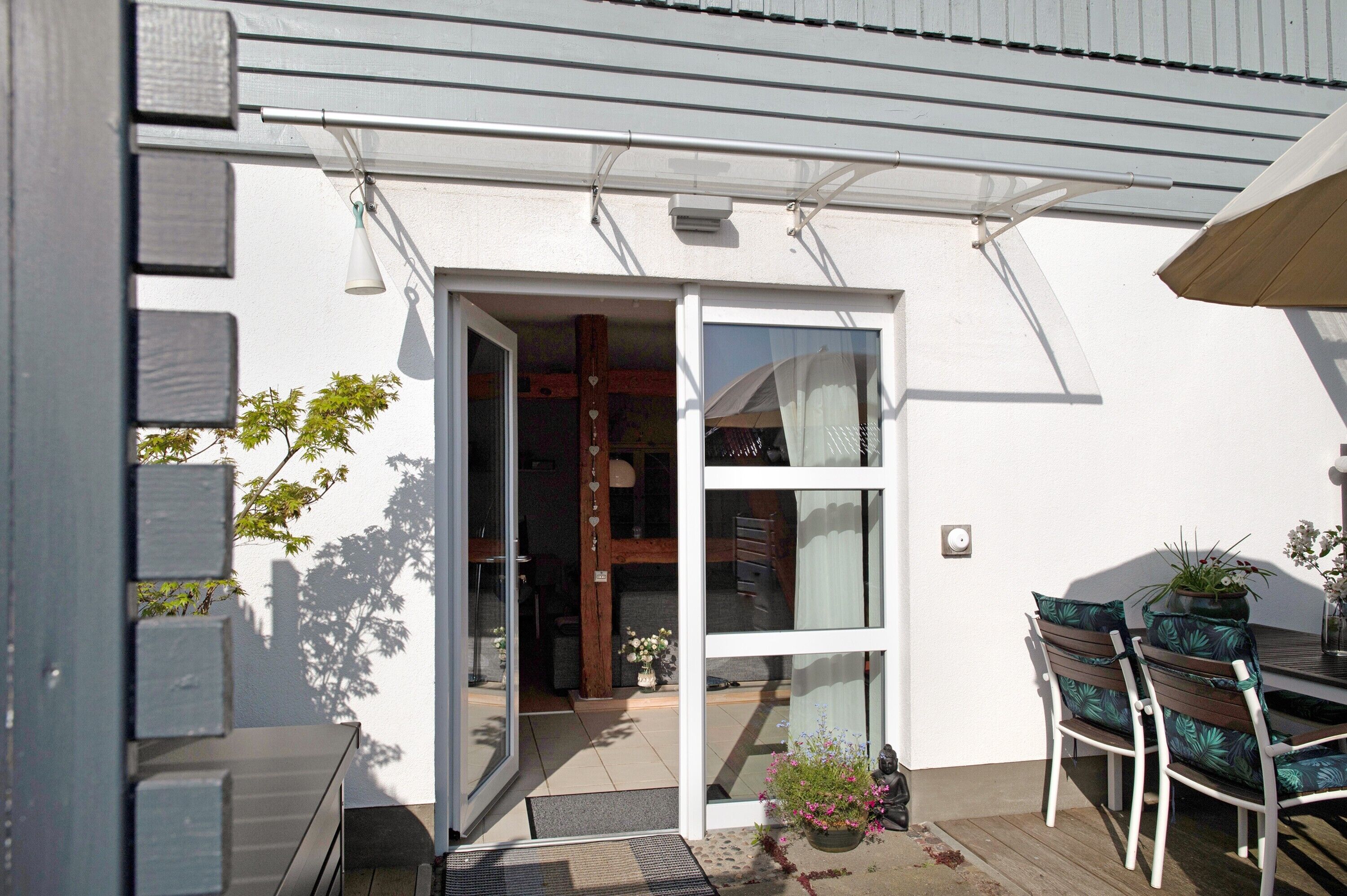 A patio area with a table and chairs, a potted plant, and a sliding glass door leading to an interior space.