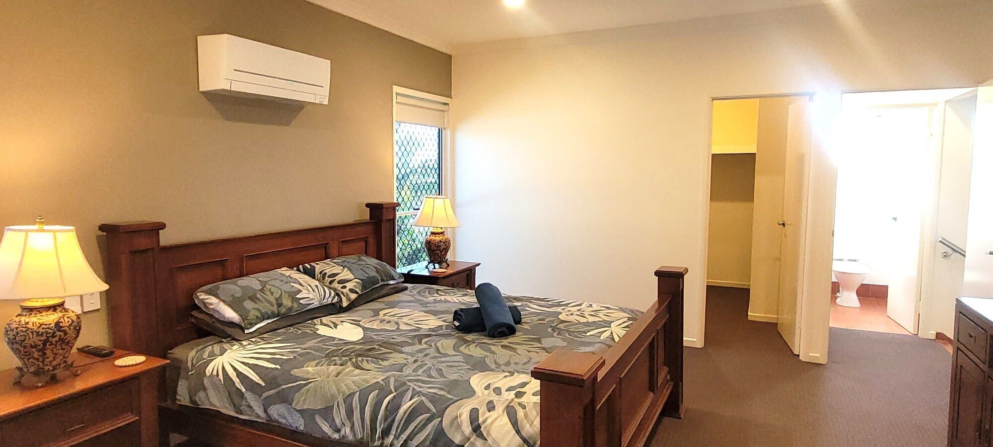 Een slaapkamer met een bed, nachtkastjes, een lamp en een raam.