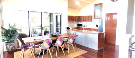 A dining area with a wooden table and chairs, a kitchen with wooden cabinets, and a large window.