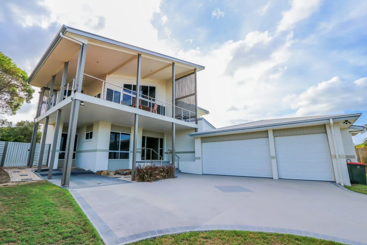 A two-story house with a balcony, a garage, and a well-maintained lawn.