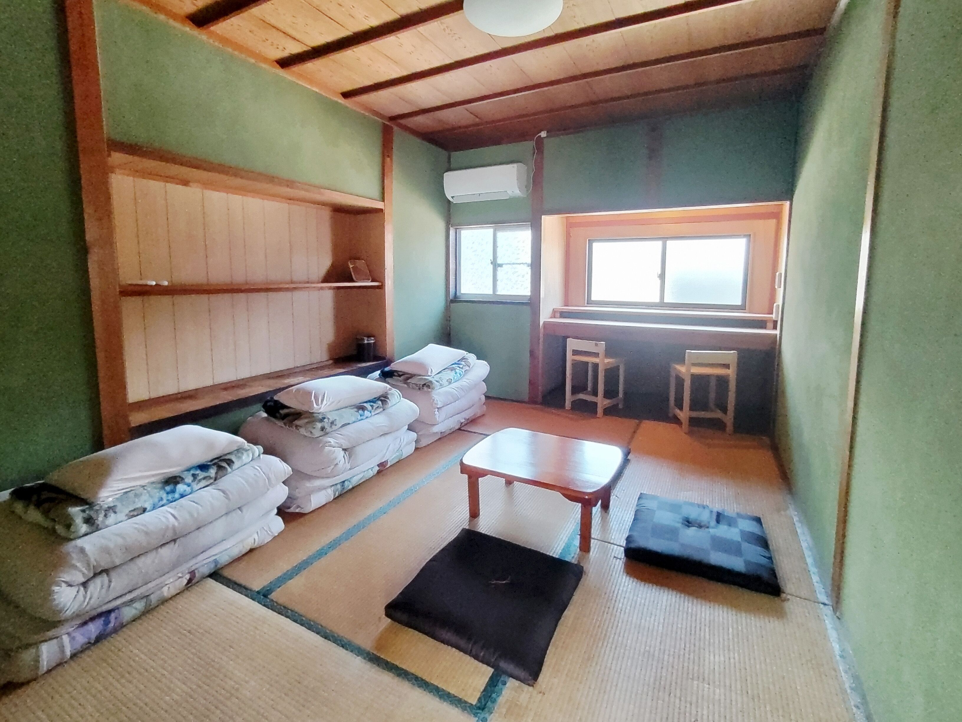 Ein kleiner Raum mit Tatami-Matten, einem niedrigen Tisch, einer Couch und einem Fenster mit Blick.