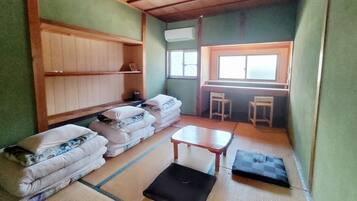 A small room with tatami mats, a low table, a sofa, and a window with a view.