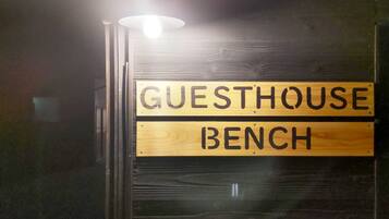 Un cartello di legno con la scritta 'GUESTHOUSE BENCH' che indica una zona riservata agli ospiti.