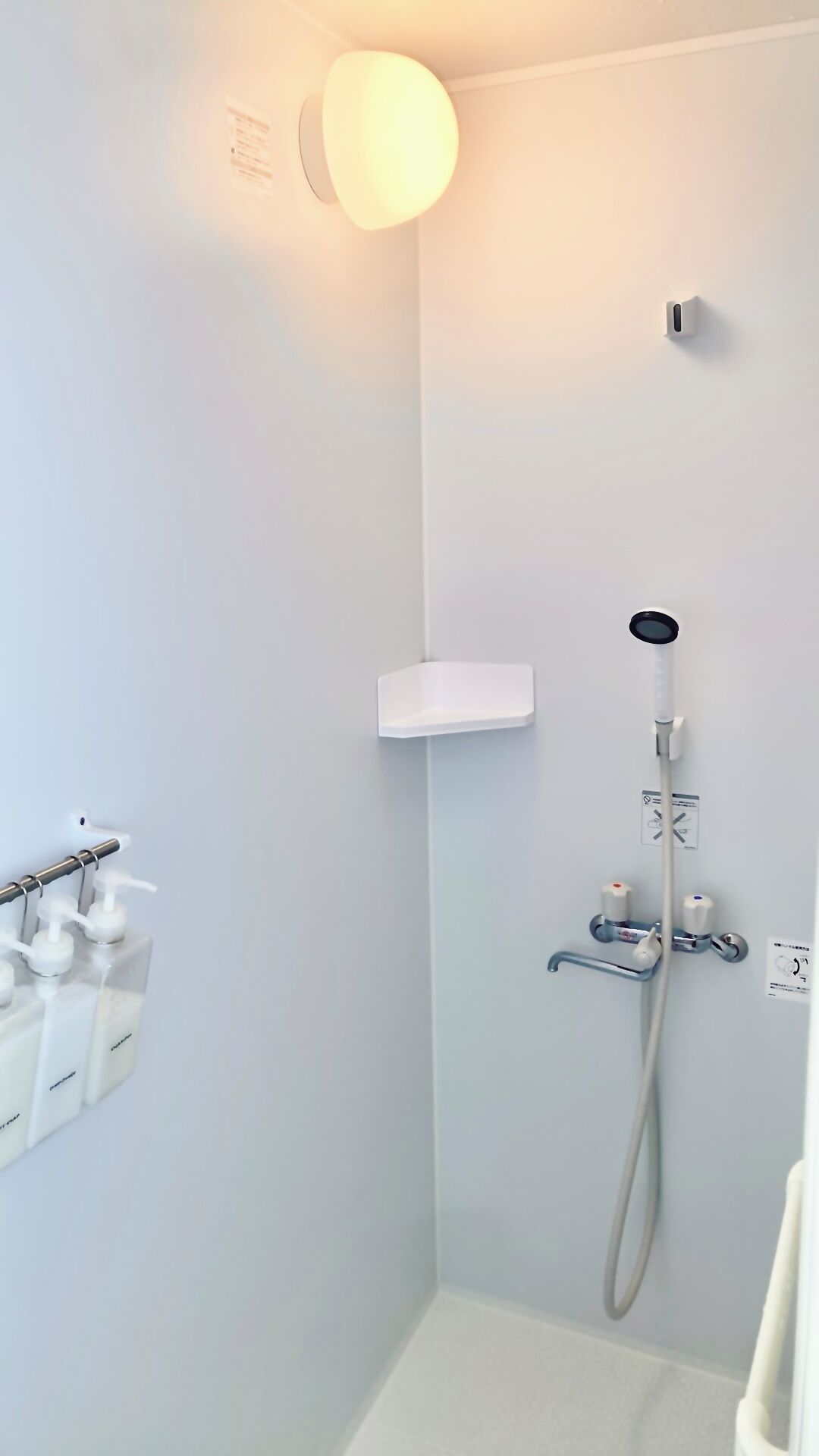 Un baño moderno con ducha, dispensador de jabón e iluminación.
