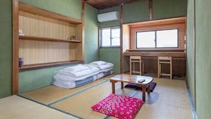 Ein traditioneller japanischer Raum mit Tatami-Böden, einem Futon, einem kleinen Holztisch und einem Fenster mit Blick.