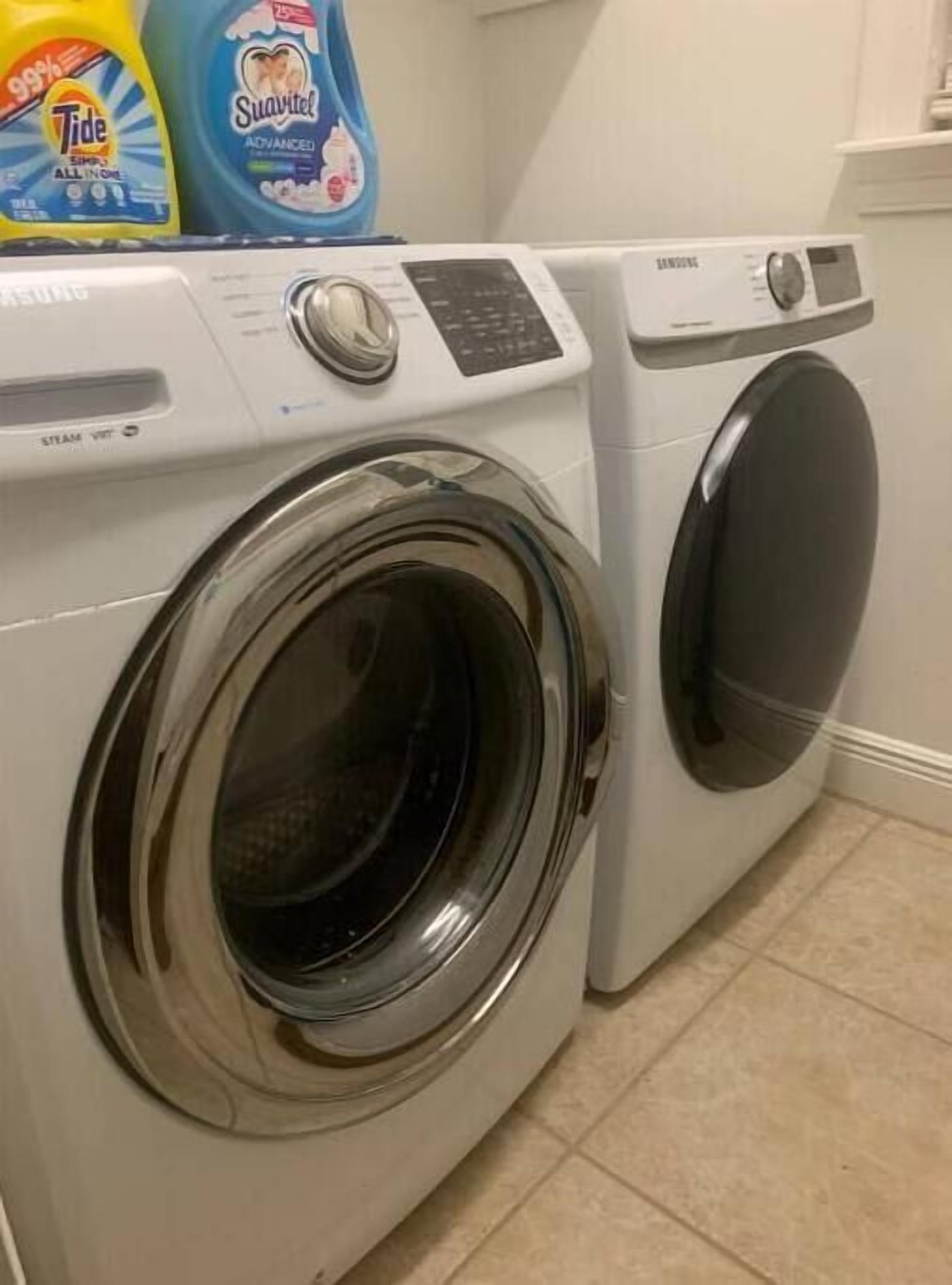 A front-loading washing machine and dryer in a laundry room.