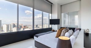 Enjoy a panoramic city view from the comfort of this stylish room, featuring a large window, a comfortable bed, and a flat-screen TV.