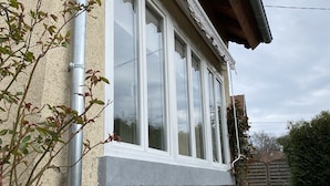 Un edificio de fachada color beige, una ventana con marco blanco y un cartel con el número 2.