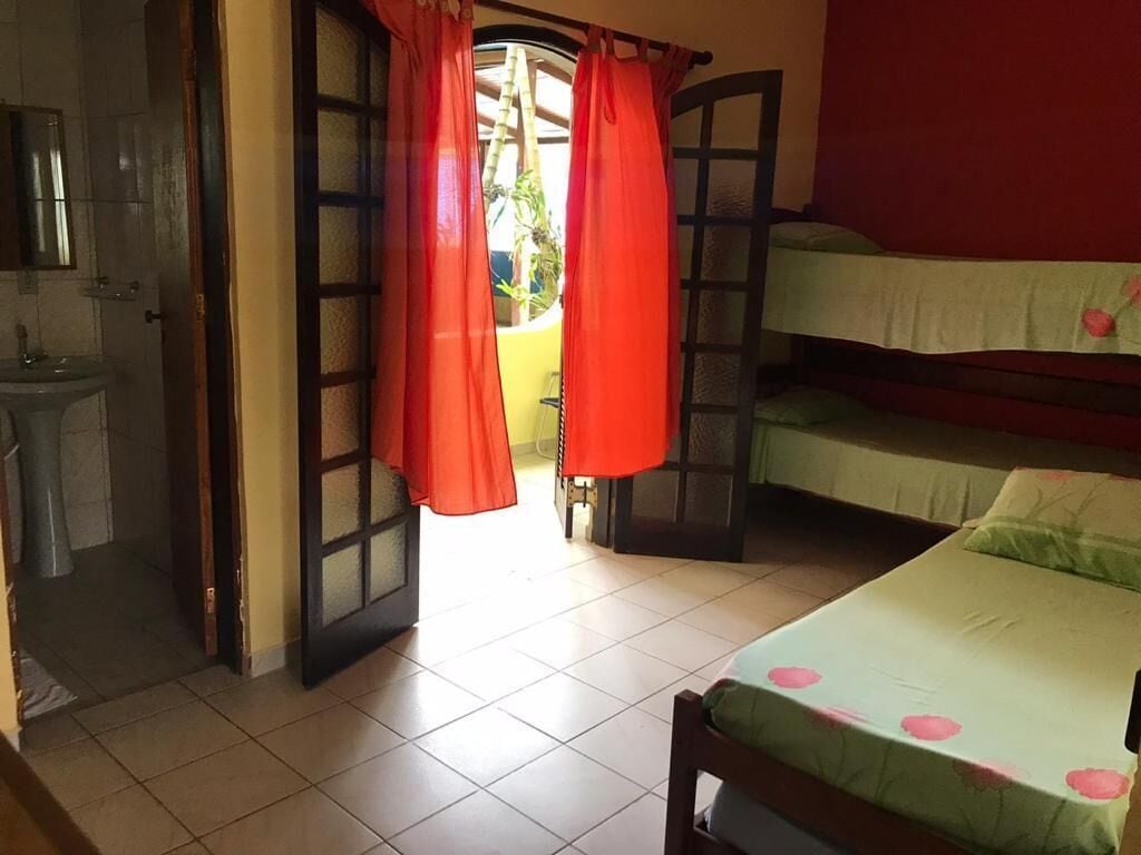 Une pièce avec un lit, un lavabo et une fenêtre avec des rideaux.