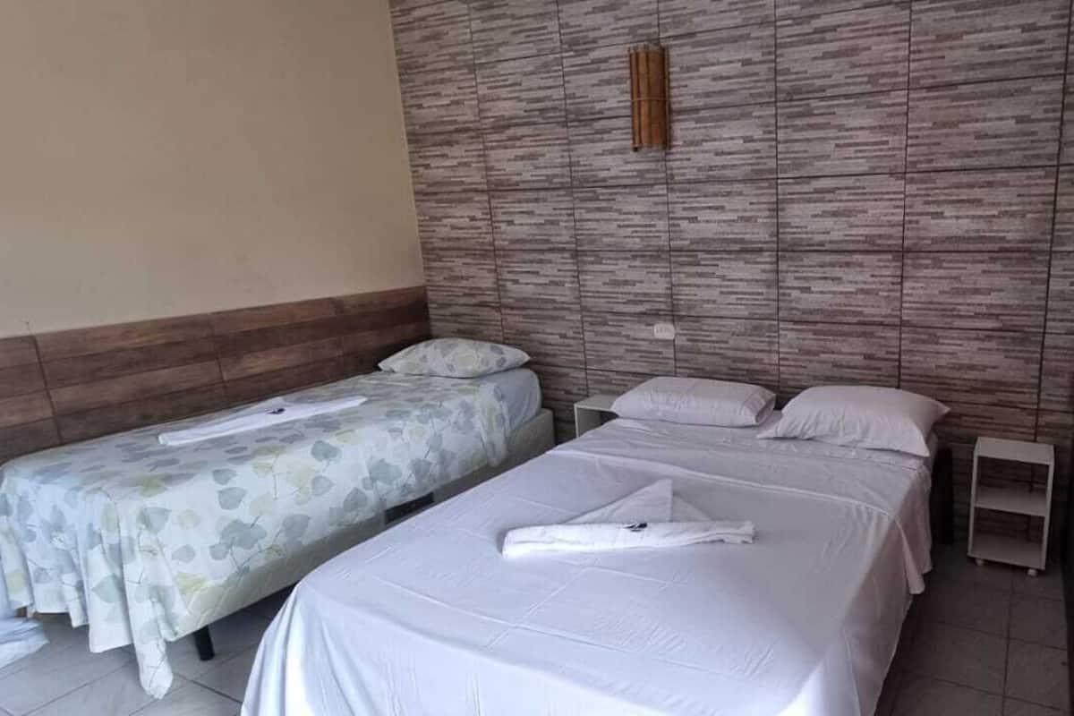 A small, clean room with two single beds, a wooden headboard, and a small shelf.