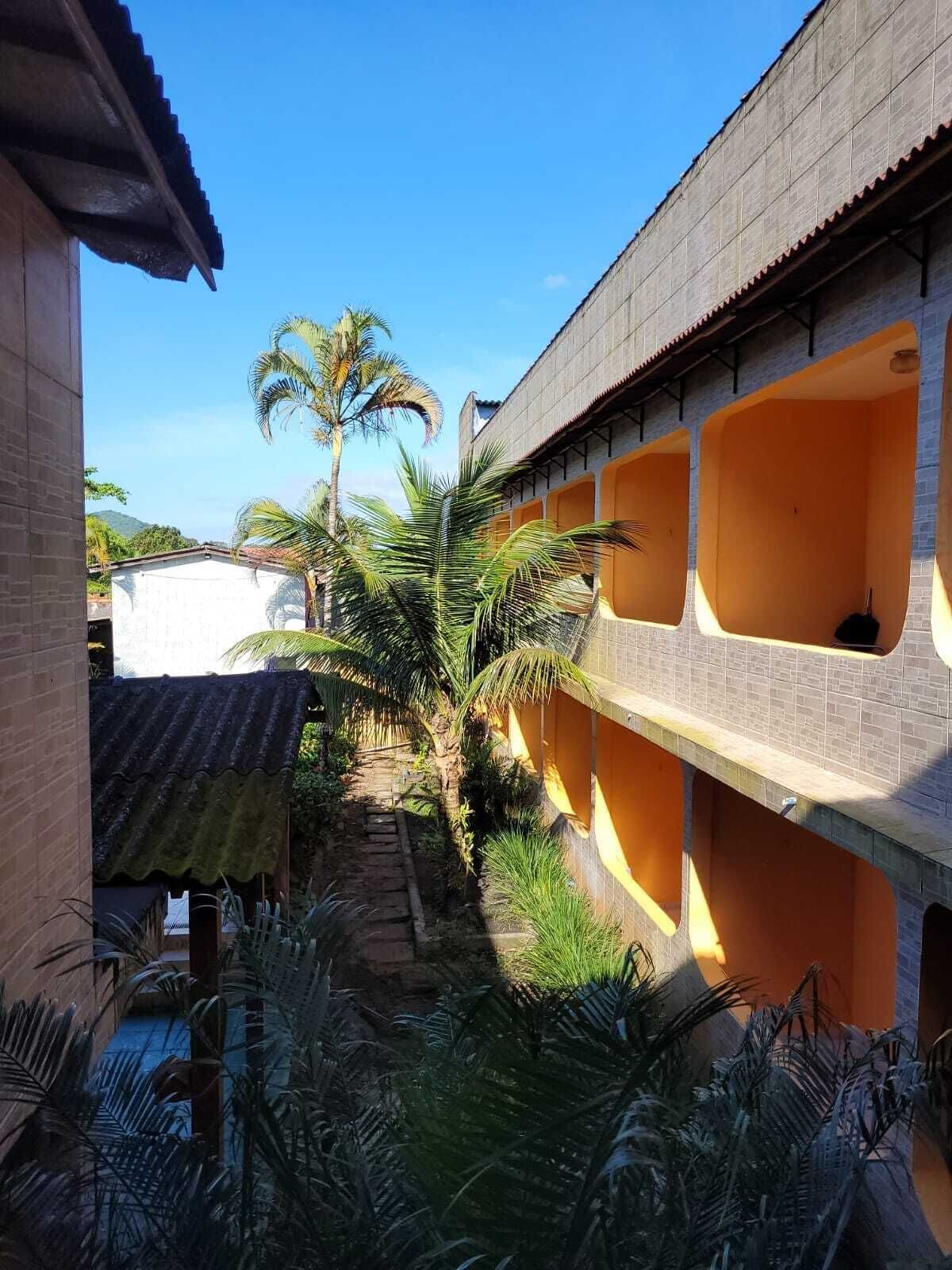 Um pátio com um caminho, palmeiras e um edifício com paredes laranja e várias janelas.