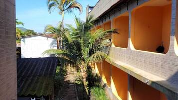 Um pátio com um caminho, palmeiras e um edifício com paredes laranja e várias janelas.