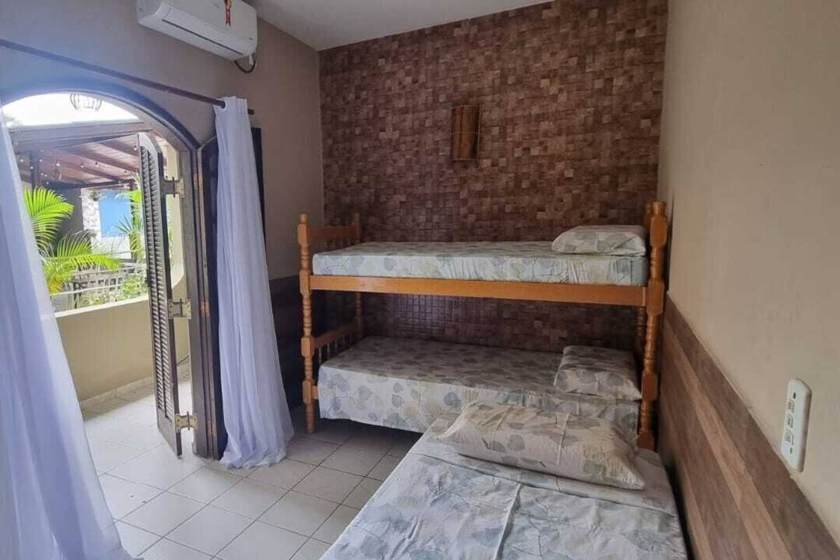 A room with a bunk bed, a small table, and a window with curtains.