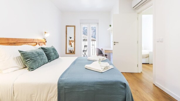 Un dormitorio con cama, escritorio, silla y espejo.