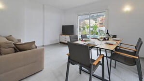 A modern living room with a sofa, dining table, chairs, and a TV. - Limoncello - Denia, Costa Blanca (Denia)